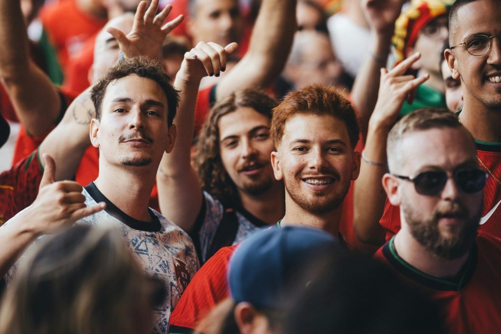 Cheerful group of soccer fans celebrating at an outdoor event during the day.